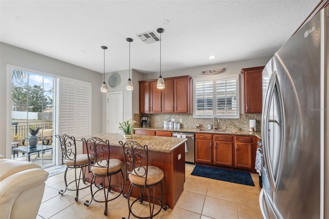 18819 Sunterra Dr, Land O Lakes, FL 34638 - kitchen with stainless steel appliances, a sink, tasteful backsplash, a kitchen island, and light stone counters