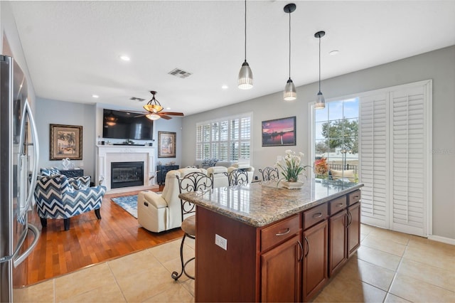 18819 Sunterra Dr, Land O Lakes, FL 34638 - kitchen featuring freestanding refrigerator, light tile patterned floors, a kitchen bar, healthy amount of natural light, and recessed lighting