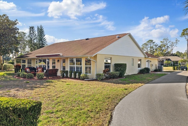 ranch-style home featuring central AC unit and a front yard