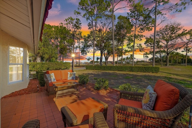 patio terrace at dusk with an outdoor living space and a yard