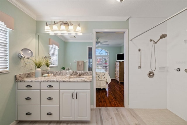 bathroom featuring wood-type flooring, vanity, tiled shower, ceiling fan, and crown molding