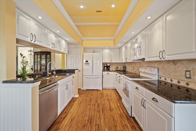 kitchen featuring sink, ornamental molding, kitchen peninsula, white appliances, and white cabinets