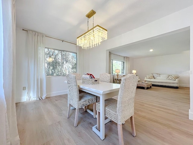 dining area with a notable chandelier, a healthy amount of sunlight, and light wood-type flooring