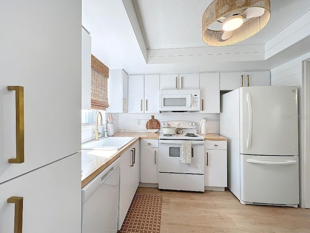 kitchen with sink, white appliances, white cabinetry, tasteful backsplash, and light hardwood / wood-style floors