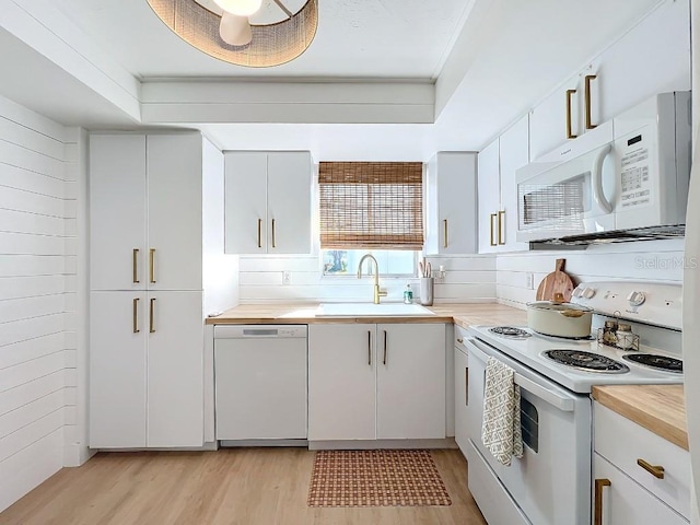 kitchen with white cabinetry, sink, white appliances, and light hardwood / wood-style flooring