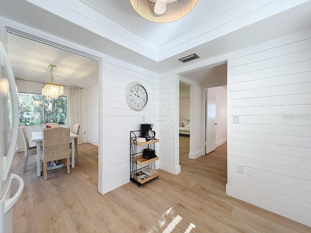 hall featuring an inviting chandelier and light hardwood / wood-style floors