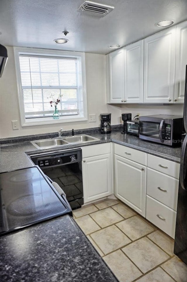 kitchen featuring sink, light tile patterned floors, white cabinets, and black appliances