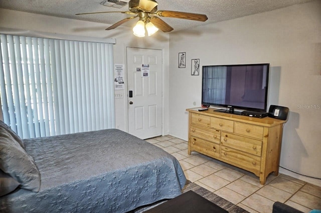 tiled bedroom with ceiling fan and a textured ceiling