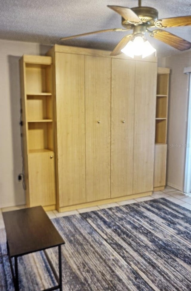 unfurnished bedroom with ceiling fan, a closet, a textured ceiling, and light tile patterned floors