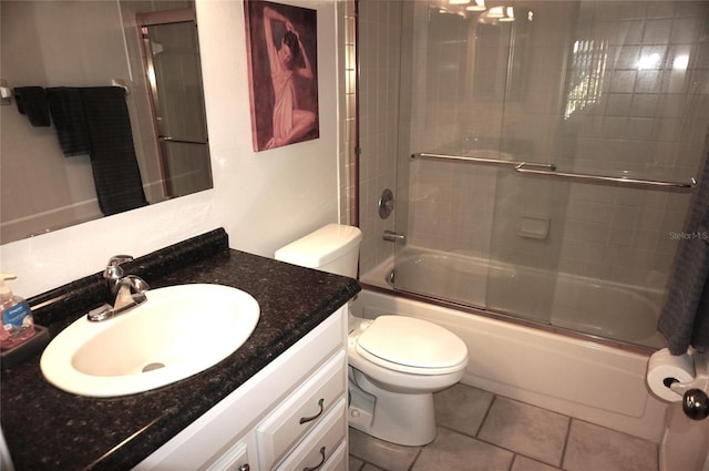 full bathroom with tile patterned flooring, bath / shower combo with glass door, vanity, and toilet