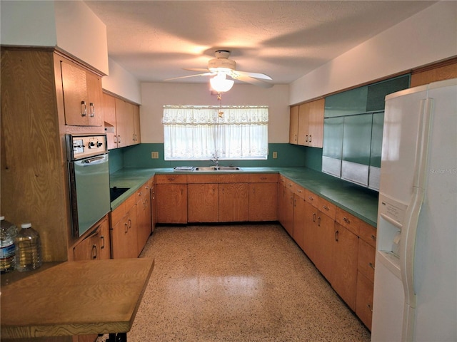 kitchen featuring sink, ceiling fan, oven, white fridge with ice dispenser, and cooktop