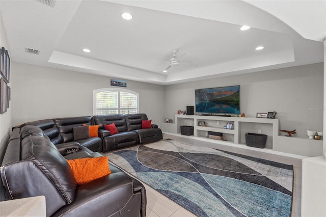 living room featuring a raised ceiling and ceiling fan