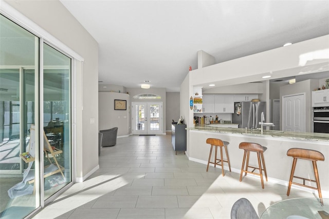 kitchen featuring a breakfast bar area, white cabinets, kitchen peninsula, stainless steel appliances, and french doors