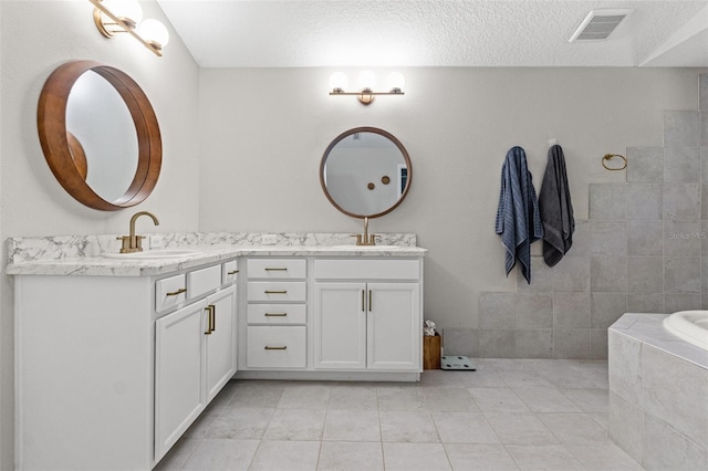 bathroom with vanity, a relaxing tiled tub, tile patterned floors, and a textured ceiling