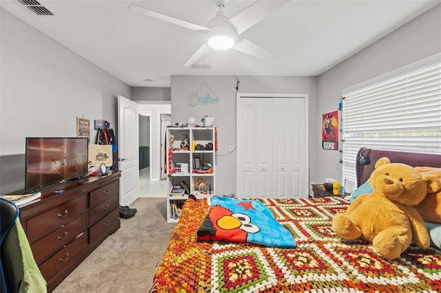 bedroom with light colored carpet, ceiling fan, and a closet