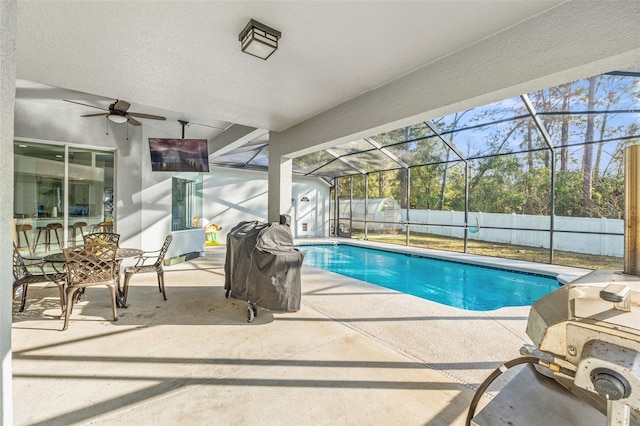 view of swimming pool featuring ceiling fan, area for grilling, glass enclosure, and a patio area