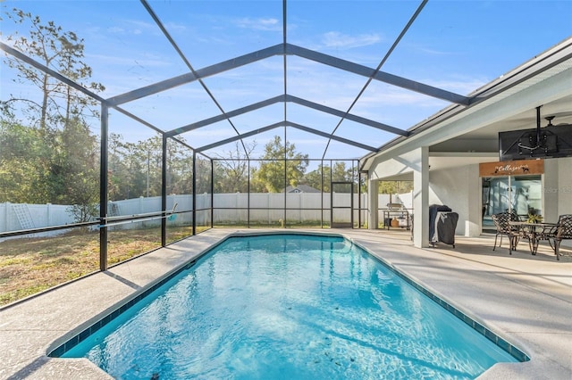 view of swimming pool with a patio area, ceiling fan, and glass enclosure