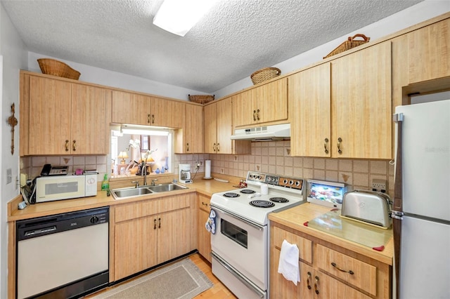 kitchen featuring light brown cabinetry, sink, backsplash, white appliances, and a textured ceiling