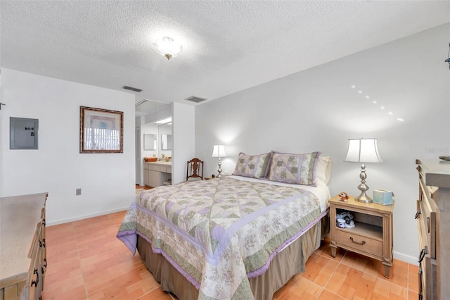 bedroom featuring electric panel, light hardwood / wood-style floors, and a textured ceiling