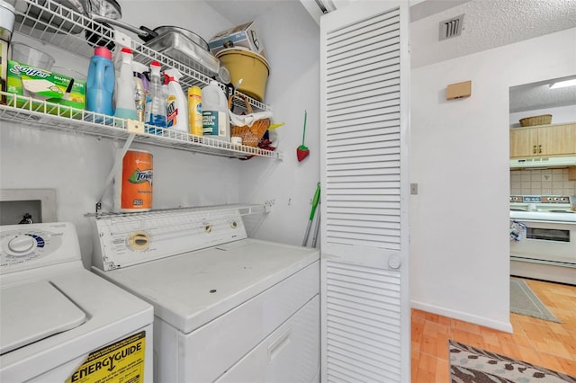 laundry room featuring hardwood / wood-style flooring, a textured ceiling, and washer and clothes dryer