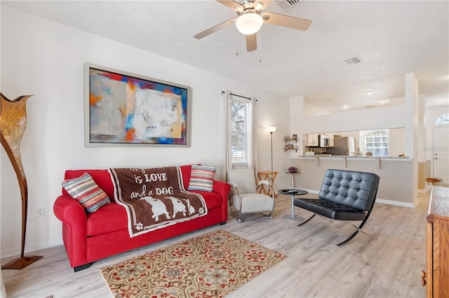 living room with ceiling fan, light hardwood / wood-style floors, and a textured ceiling