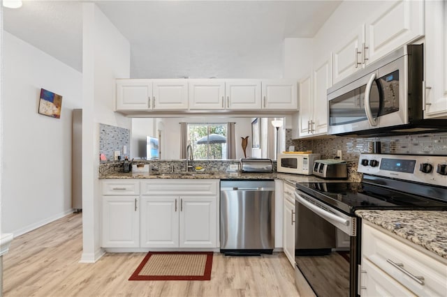 kitchen with light stone counters, sink, white cabinetry, and appliances with stainless steel finishes