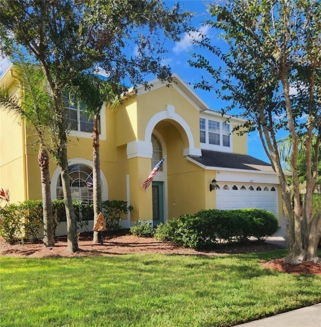 mediterranean / spanish-style house with a front lawn, a garage, and stucco siding