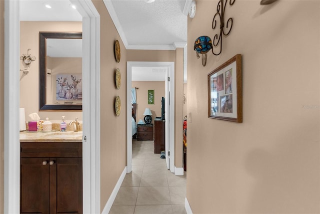 hall featuring light tile patterned flooring, sink, a textured ceiling, and crown molding