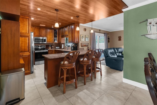 kitchen featuring a breakfast bar, ornamental molding, kitchen peninsula, pendant lighting, and stainless steel appliances