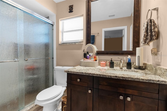 bathroom with walk in shower, vanity, and toilet