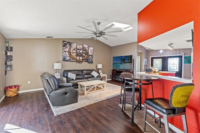 living room featuring ceiling fan, dark wood-type flooring, french doors, and vaulted ceiling with skylight