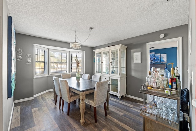 dining space with dark hardwood / wood-style floors and a textured ceiling