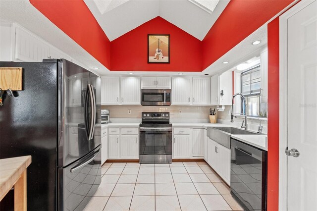 kitchen featuring vaulted ceiling, light tile patterned flooring, appliances with stainless steel finishes, sink, and white cabinets