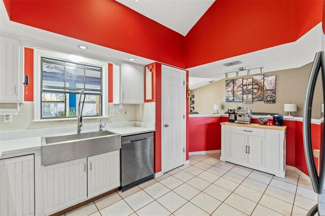 kitchen with light tile patterned flooring, tasteful backsplash, white cabinetry, sink, and stainless steel dishwasher