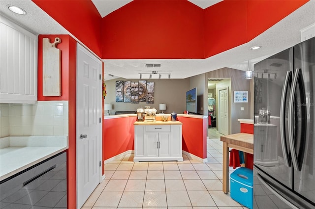 kitchen featuring white cabinetry, black dishwasher, decorative backsplash, fridge, and light tile patterned floors