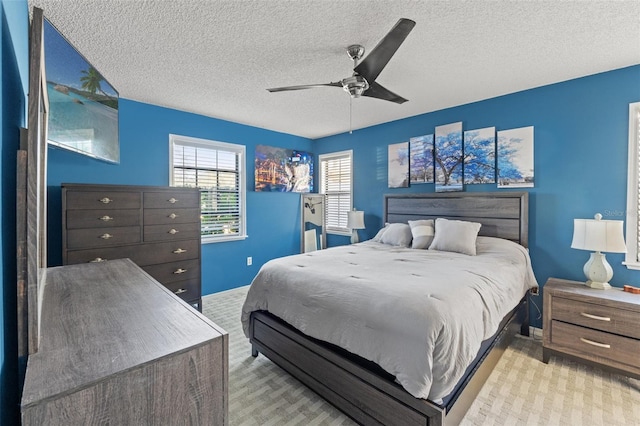 carpeted bedroom featuring a textured ceiling and ceiling fan