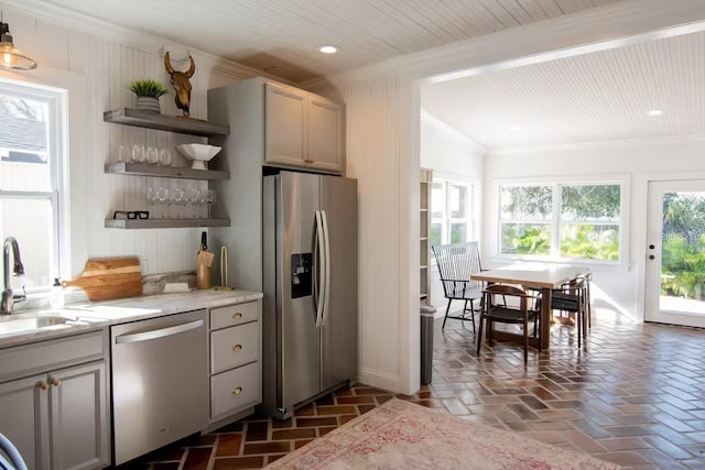 kitchen with sink, crown molding, gray cabinets, appliances with stainless steel finishes, and light stone counters