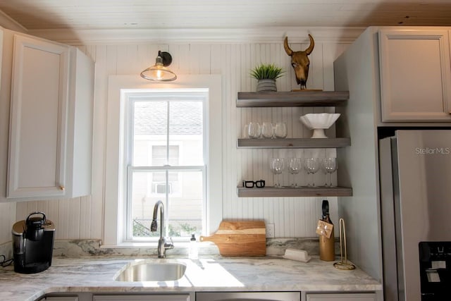 kitchen with white cabinetry, stainless steel fridge with ice dispenser, light stone counters, and sink