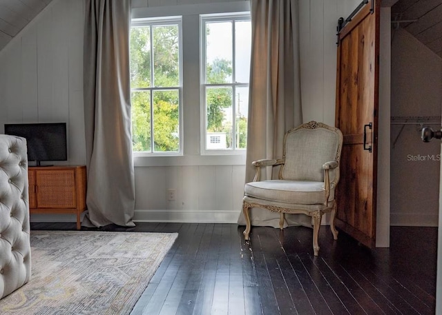 sitting room featuring a barn door and dark hardwood / wood-style floors