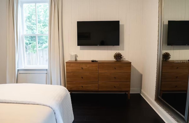 bedroom with multiple windows and dark hardwood / wood-style floors