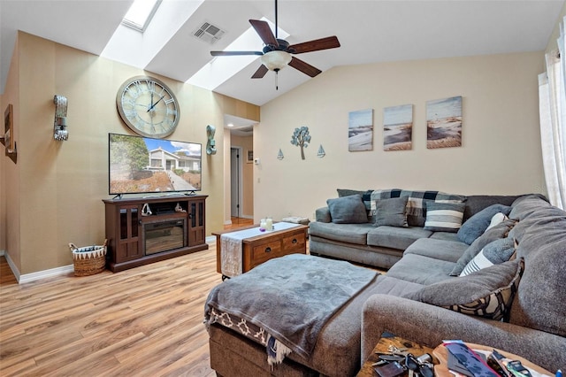 living room featuring ceiling fan, light hardwood / wood-style floors, and vaulted ceiling with skylight