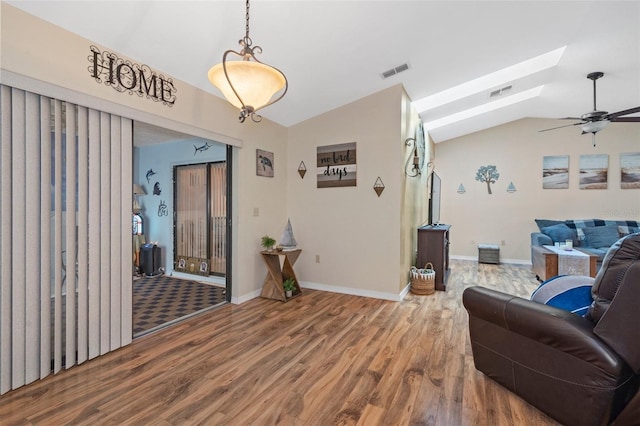 living room with ceiling fan, hardwood / wood-style flooring, and vaulted ceiling with skylight