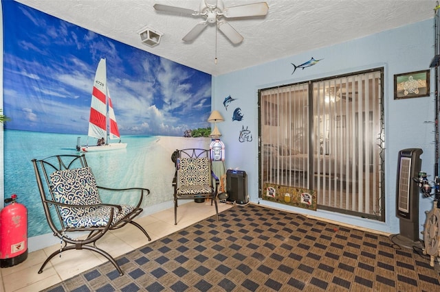 sitting room featuring ceiling fan, a water view, tile patterned floors, and a textured ceiling