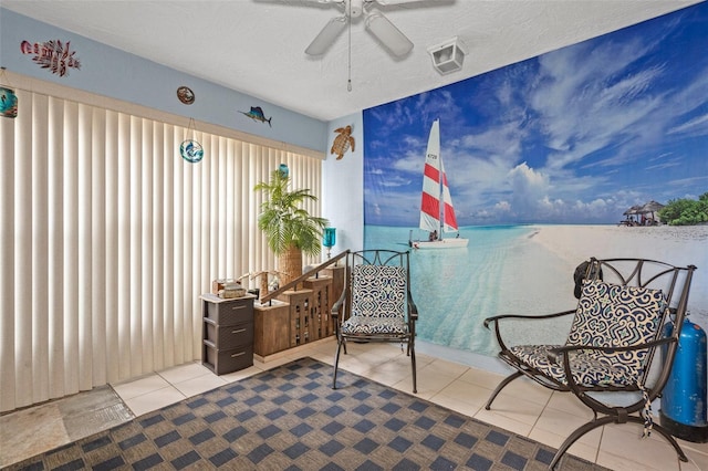 living area with tile patterned flooring, ceiling fan, a water view, and a textured ceiling