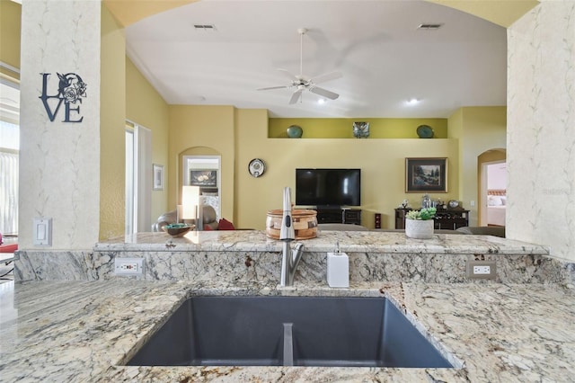 kitchen with sink, light stone countertops, and ceiling fan