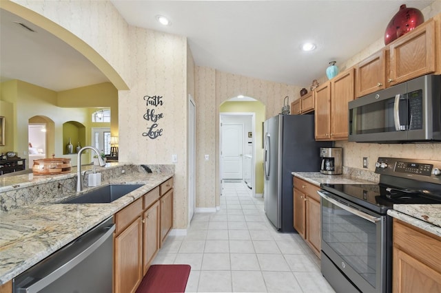 kitchen featuring sink, light tile patterned floors, light stone countertops, and appliances with stainless steel finishes