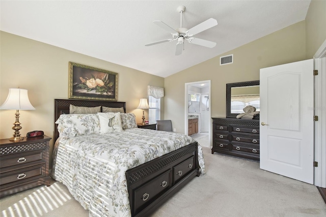 bedroom featuring ceiling fan, light colored carpet, lofted ceiling, and ensuite bath