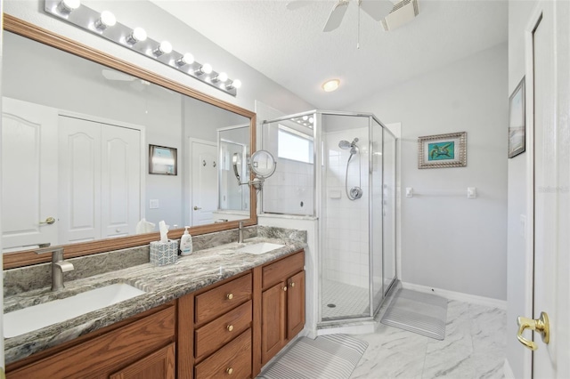 bathroom featuring ceiling fan, vanity, an enclosed shower, and a textured ceiling