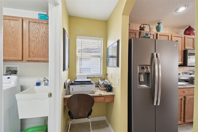 kitchen featuring washer / dryer, sink, light tile patterned floors, stainless steel appliances, and a textured ceiling