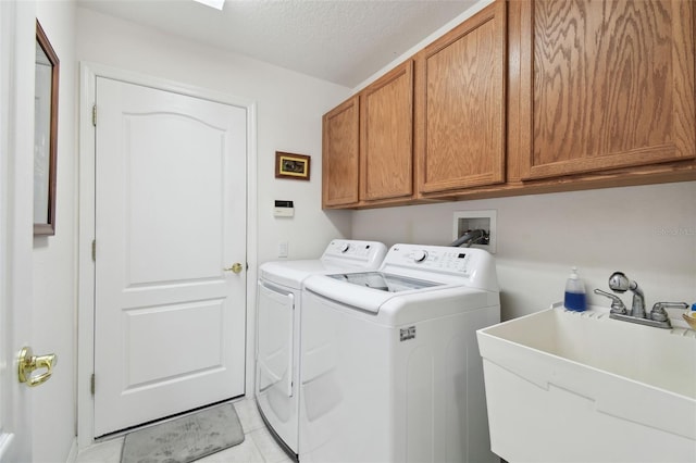 clothes washing area featuring cabinets, sink, a textured ceiling, and washer and clothes dryer